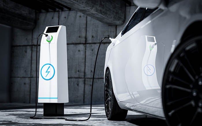 A white Ford Mustang Mach E electric SUV is charging in a public parking lot.