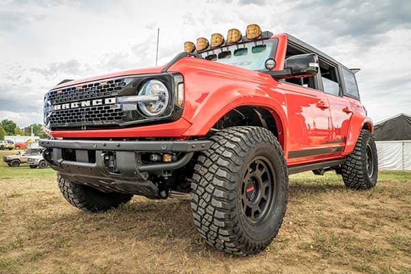 The Ford Bronco showcases its off-road features as it conquers rugged hill terrain in low-light conditions.